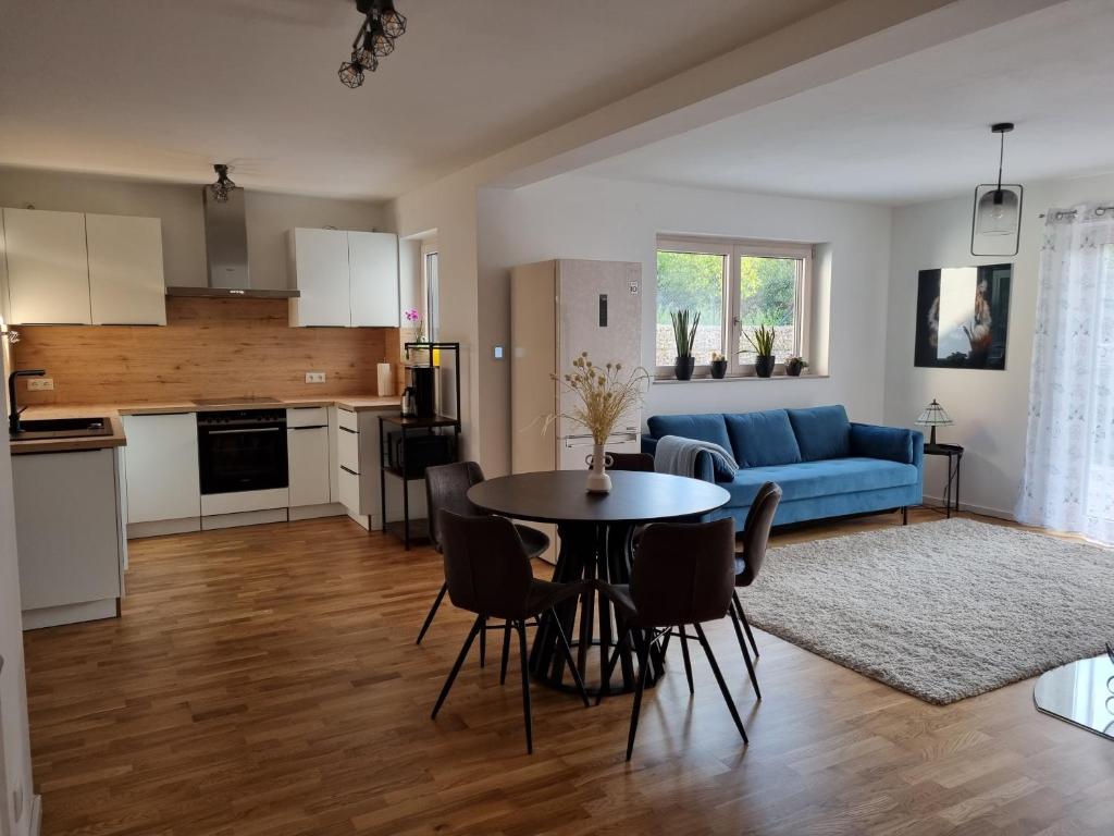 un soggiorno con tavolo e divano blu di Gemütliche Premium Ferienwohnung mit Terrasse nähe S-Bahn a Burgthann