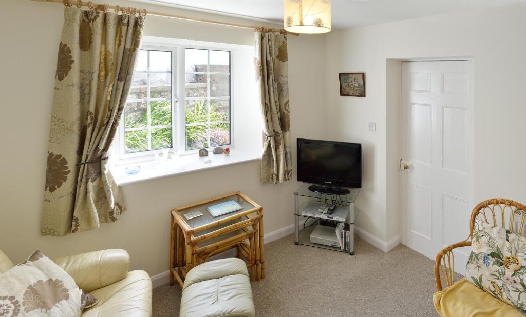 a living room with a couch and a tv and a window at Cronk Darragh Cottage in Castletown