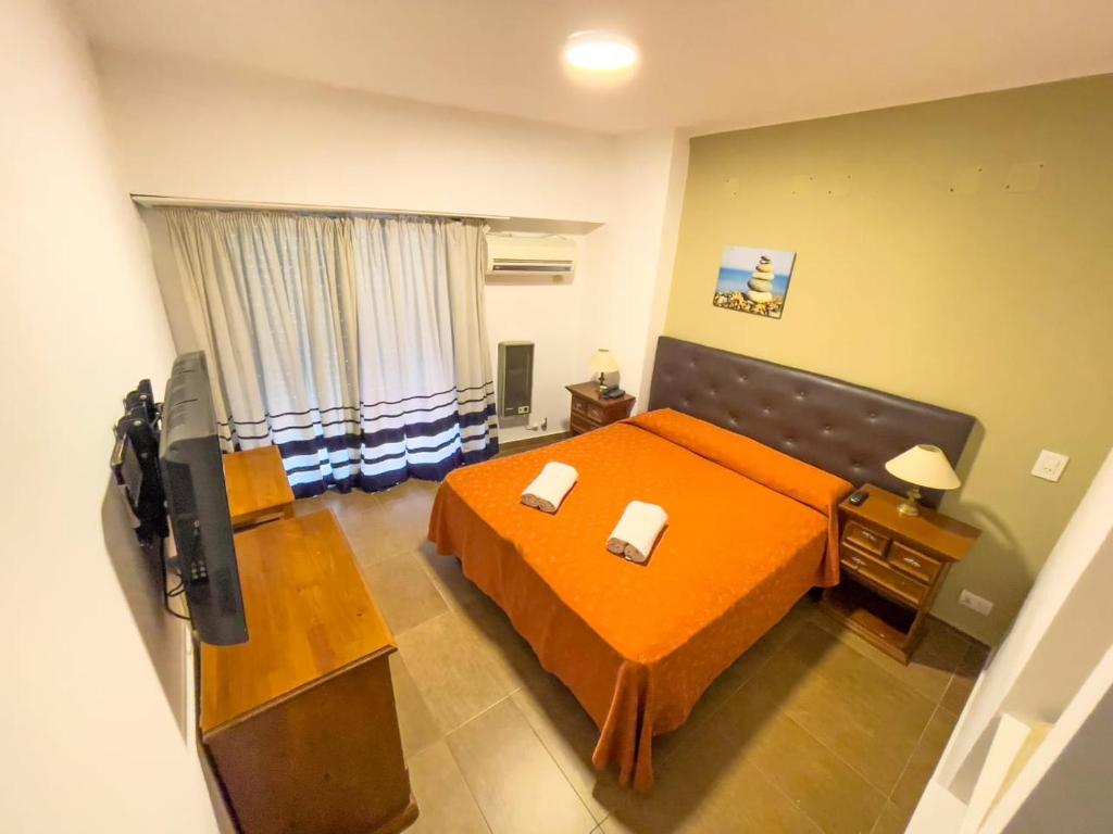 um quarto com uma cama laranja e uma televisão em Hotel Monterrey em Termas de Rio Hondo