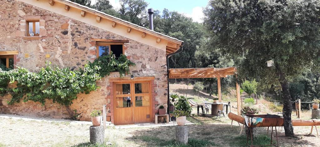 Casa de piedra con puerta de madera y mesa en La Paradella - Apartamento de uso turístico, en Arbúcies