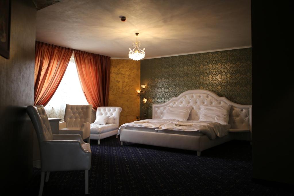 a bedroom with a white bed and a chair at Hotel Kotva in Bratislava