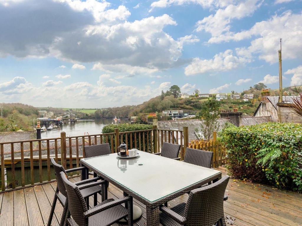 a table and chairs on a deck with a view of a river at Larboard in Fowey
