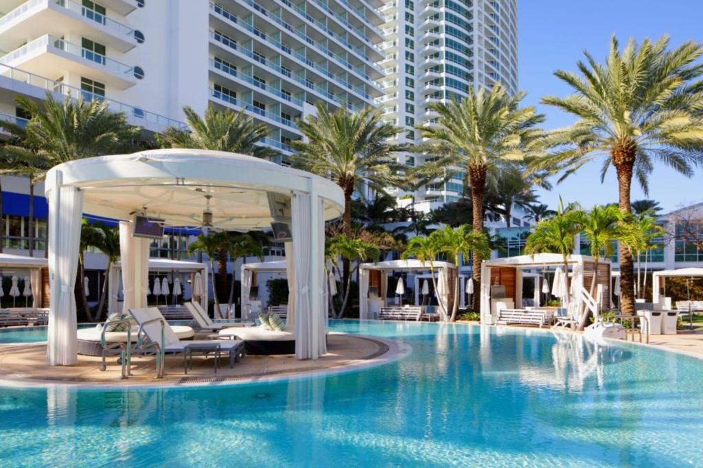 a pool at a resort with chairs and an umbrella at One-Bedroom Apartment in Miami Beach