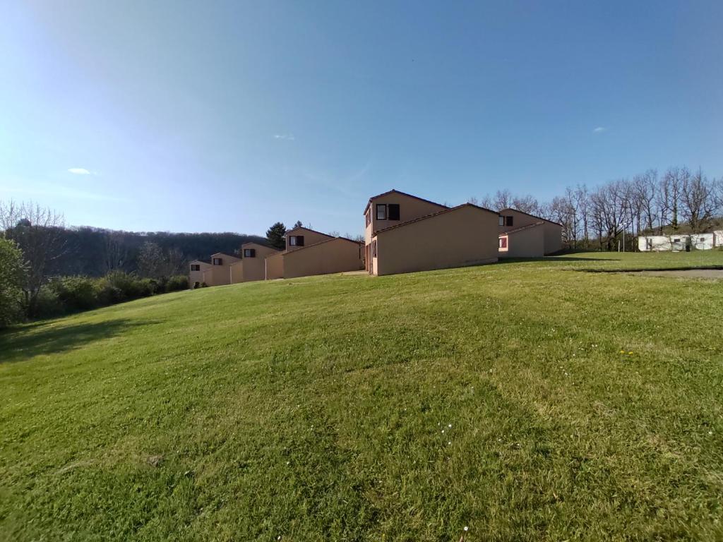 a large grassy field with houses in the background at Village Bord de Ciel in Caylus