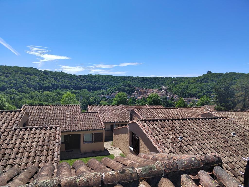 a group of roofs with mountains in the background at Village Bord de Ciel in Caylus