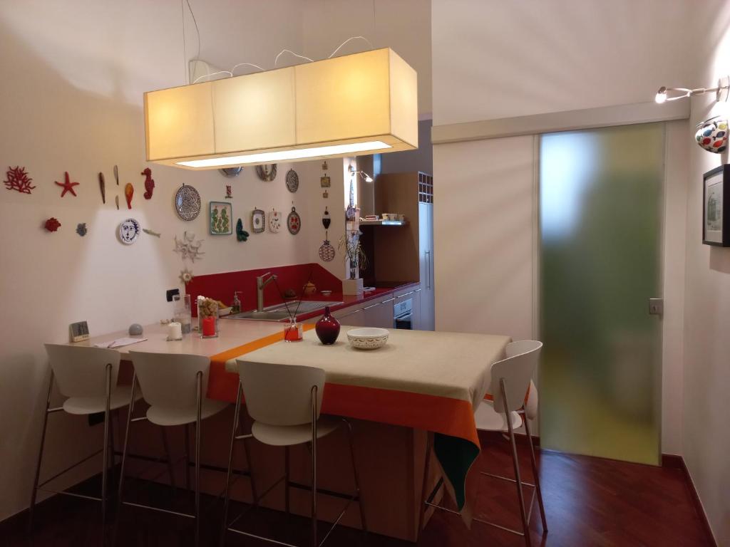 uma cozinha com uma grande ilha com cadeiras brancas e uma bancada em Interno10 em Bari