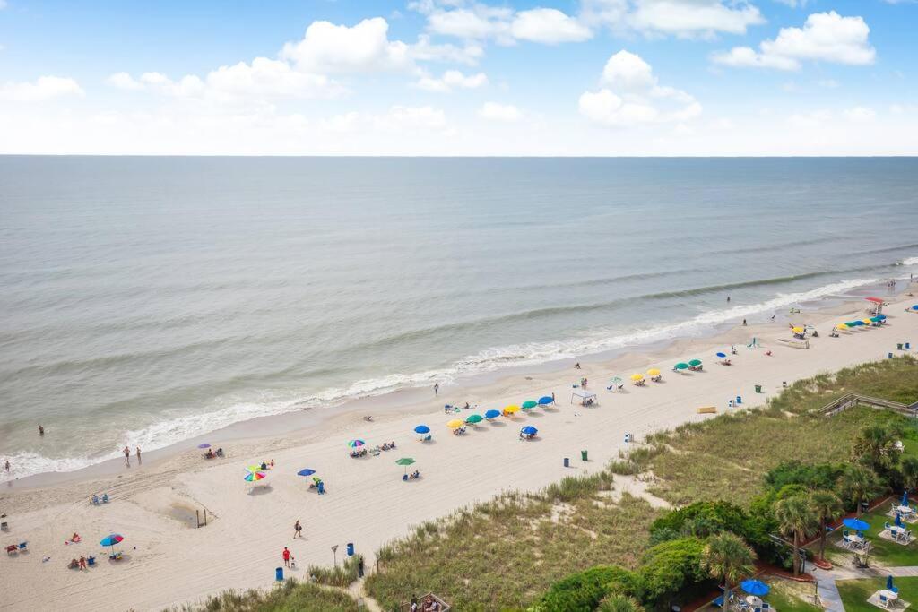 eine Luftansicht auf einen Strand mit Menschen und Sonnenschirmen in der Unterkunft Oceanfront 3BR/2BA, Ocean Reef, Waterpark in Myrtle Beach