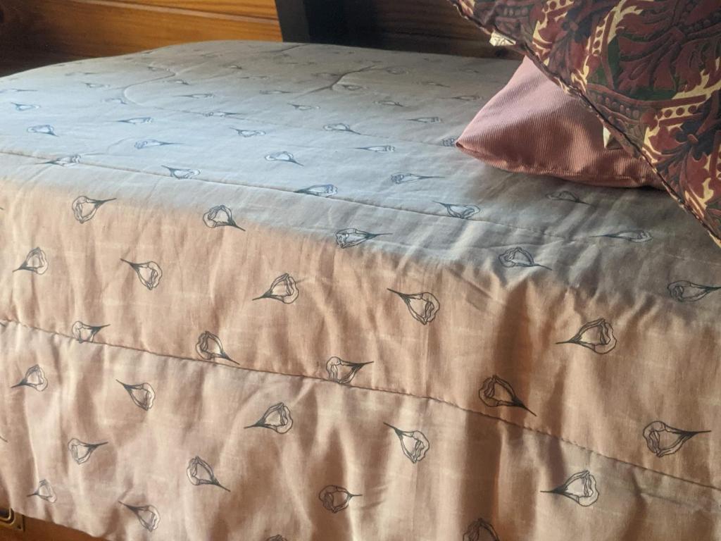 a bed with a tan sheet with butterflies on it at Habitación Boutique in Villa Alsina