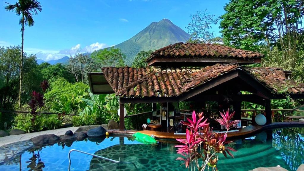 a resort with a pool with a mountain in the background at Hotel Mountain Paradise in Fortuna