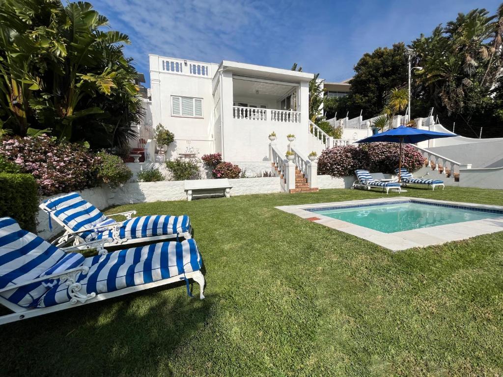 a yard with two lawn chairs and a swimming pool at Villa on Camps Bay Drive in Cape Town