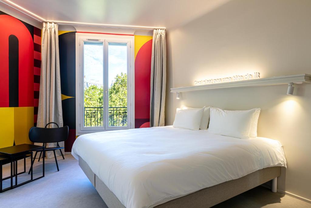 Un dormitorio con una gran cama blanca y una ventana en Graphik Montparnasse en París