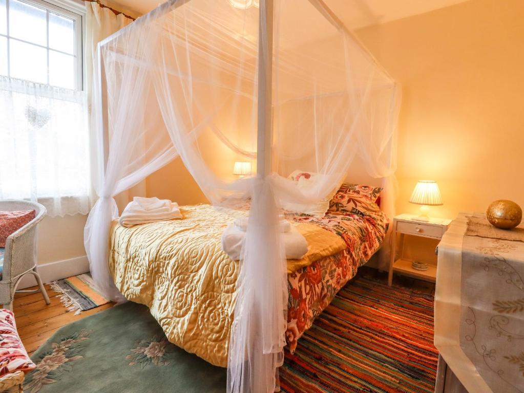 a bedroom with a bed with a canopy at Bumble Bee Cottage in Faversham