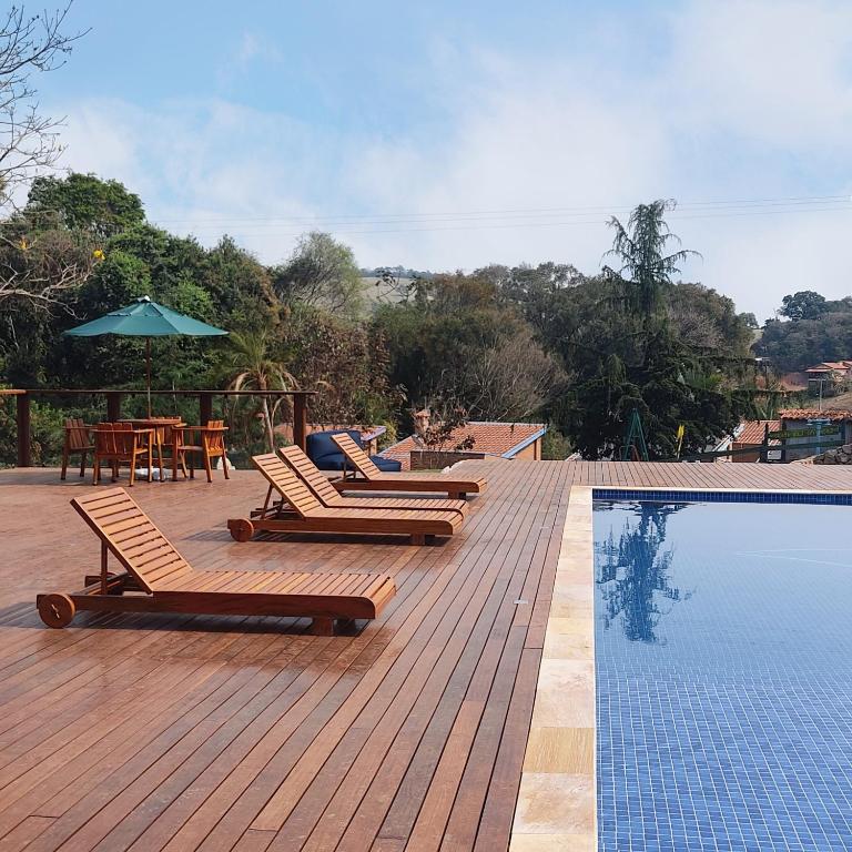 a row of lounge chairs next to a swimming pool at Encantos do Vale Pousada e SPA Cultural in Bueno Brandão