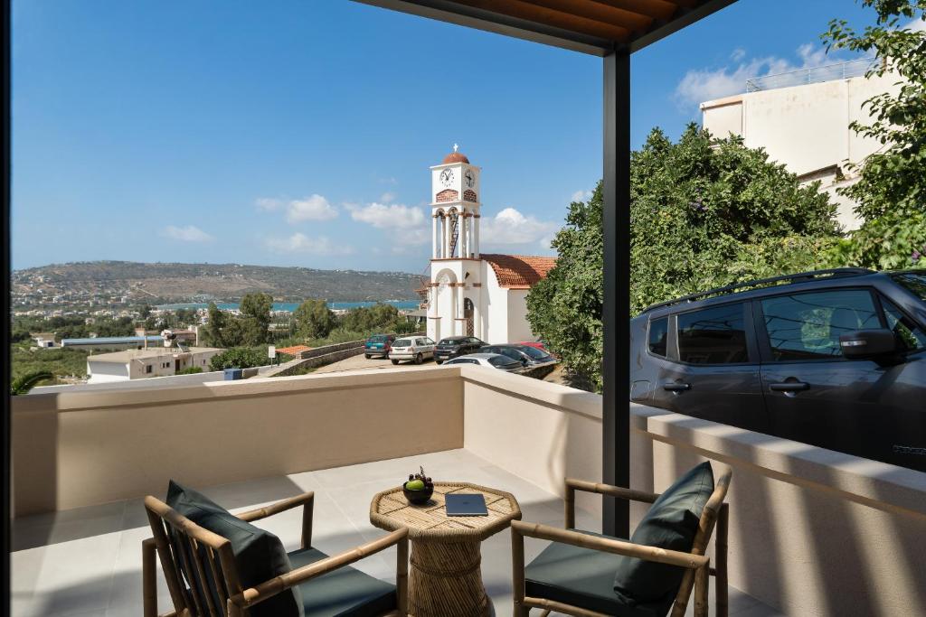 un balcone con tavolo, sedie e torre dell'orologio. di KOEV slow living a Tsikalariá