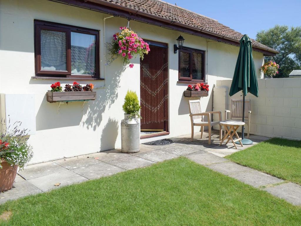 a white house with a patio and an umbrella at The Stable in Lympsham