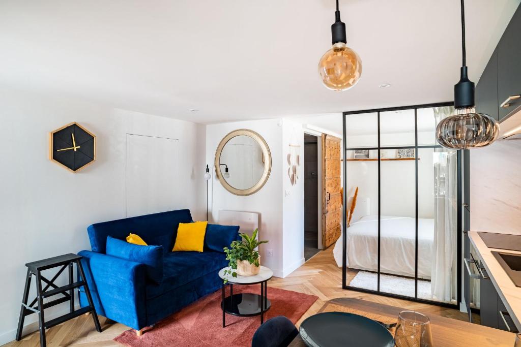 a living room with a blue couch and a bedroom at Charmant Studio paisible dans le Centre du Village in Échenevex