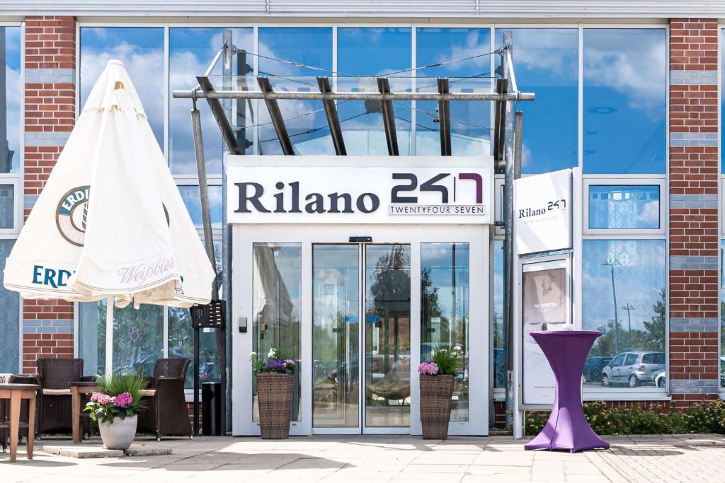 a woman standing outside of a store with a pink umbrella at Rilano 24/7 Hotel Wolfenbüttel in Wolfenbüttel