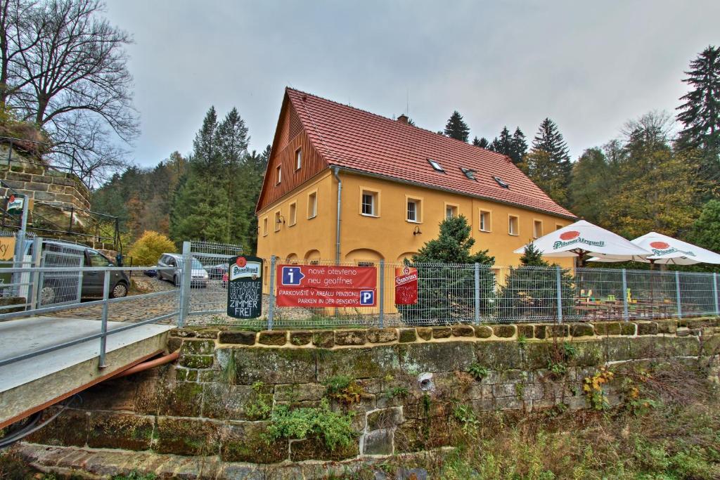 a yellow building with a fence next to a bridge at Penzion U Vyhlídky in Chřibská