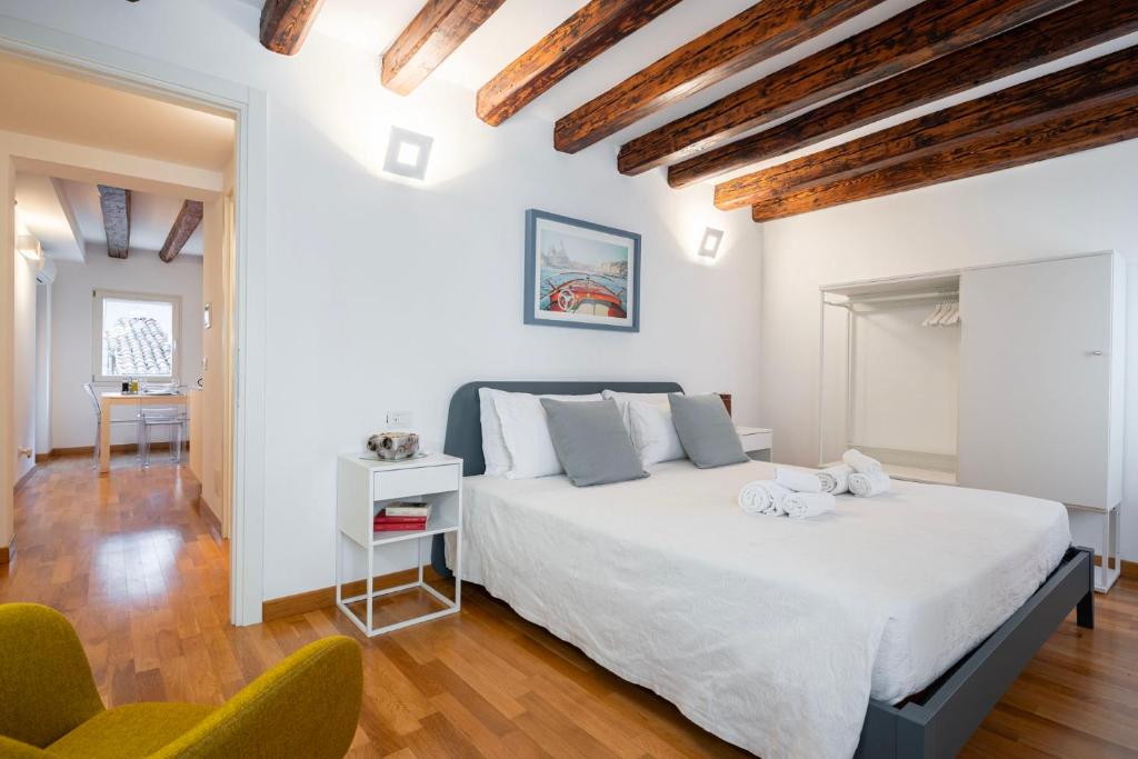 una camera da letto con un grande letto bianco e due sedie di Ca' Laura - San Marco Canal View a Venezia