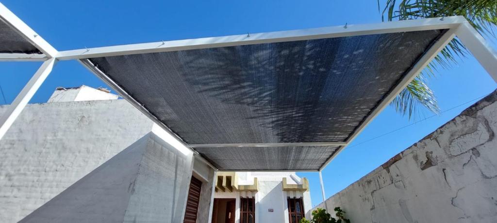 Sierras Altas Alojamientos في فيلا كارلوس باز: مظلة على مبنى به نخلة