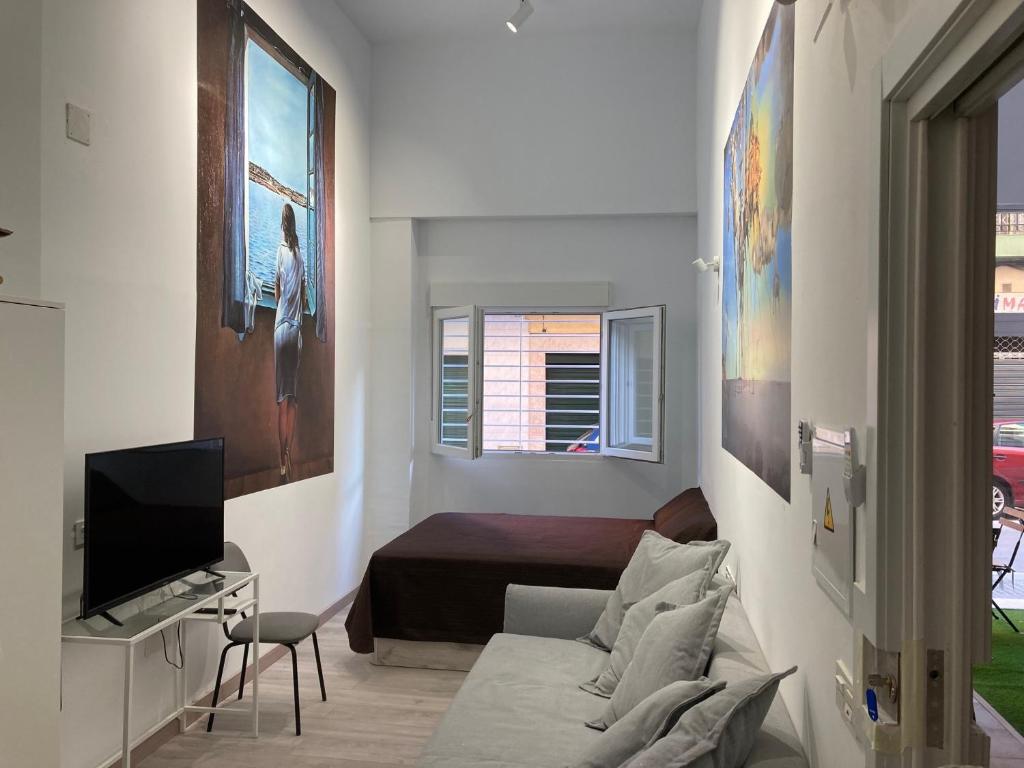 Sala de estar blanca con sofá y TV en Golondrinas de Malaga "Apartamentos con mucho Arte" y terraza solarium en coliving, en Málaga