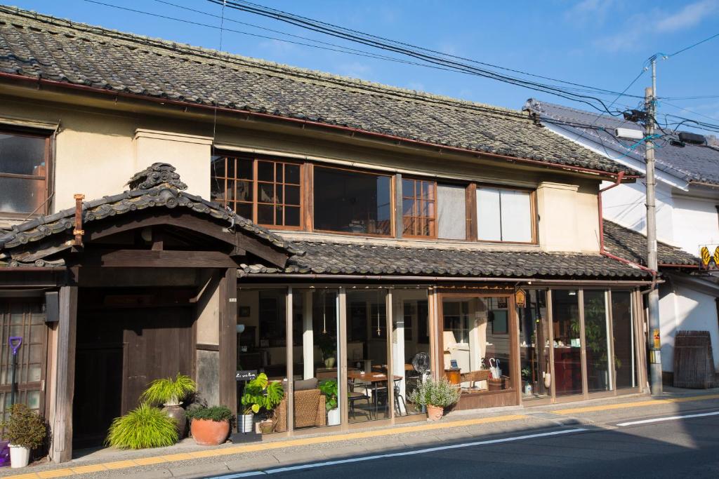 un edificio antiguo con ventanas y plantas en una calle en Guest House Kura, en Suzaka