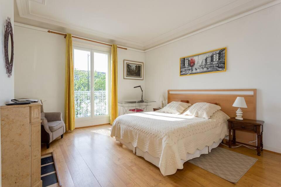sypialnia z dużym łóżkiem i oknem w obiekcie J'aime Paris 1st w mieście Boulogne-Billancourt