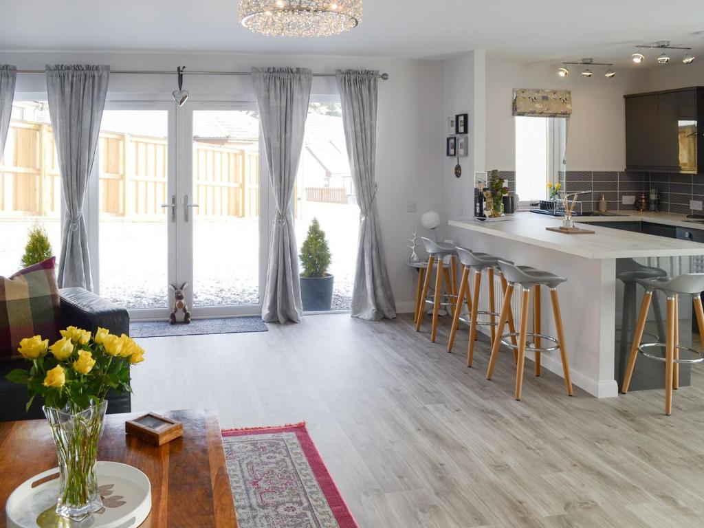 a kitchen and living room with a table and chairs at Rose Cottage in Dingwall