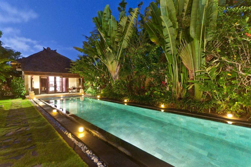 a swimming pool in front of a house with lights at Villa Blubambu in Seminyak