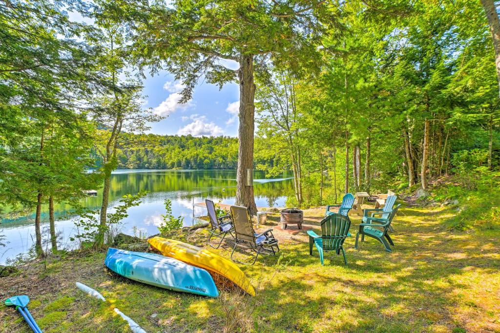 a group of chairs and kayaks sitting next to a lake at Dreamy Bucksport Hideaway on Freshwater Pond! in Bucksport