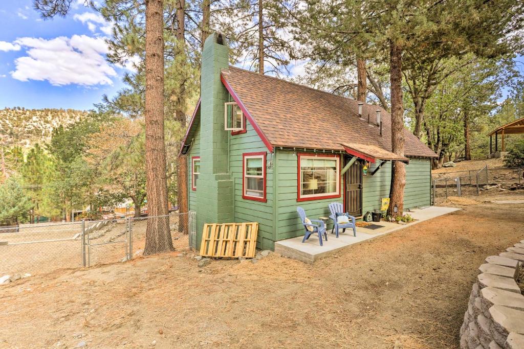 una pequeña casa verde con dos sillas delante en Wrightwood Cabin with Cozy Interior!, en Wrightwood