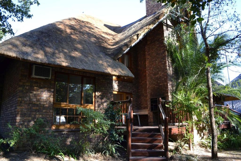 una casa de ladrillo con techo de paja en Kruger Park Lodge - Golf Safari SA, en Hazyview