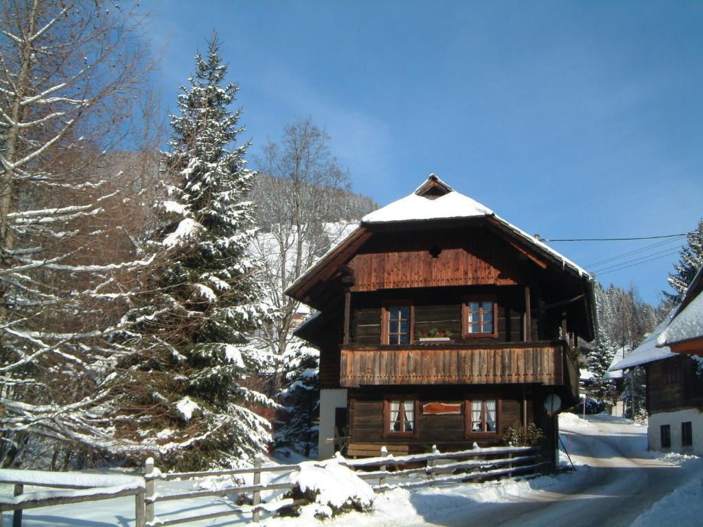 a log cabin in the snow with a christmas tree at Haus am Bach in Bad Kleinkirchheim