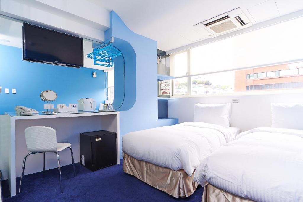 two beds in a room with a blue wall at Forever Inn in Taipei