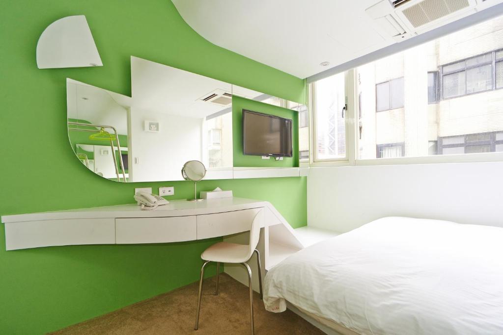 a bedroom with a bed and a desk and a tv at Forever Inn in Taipei