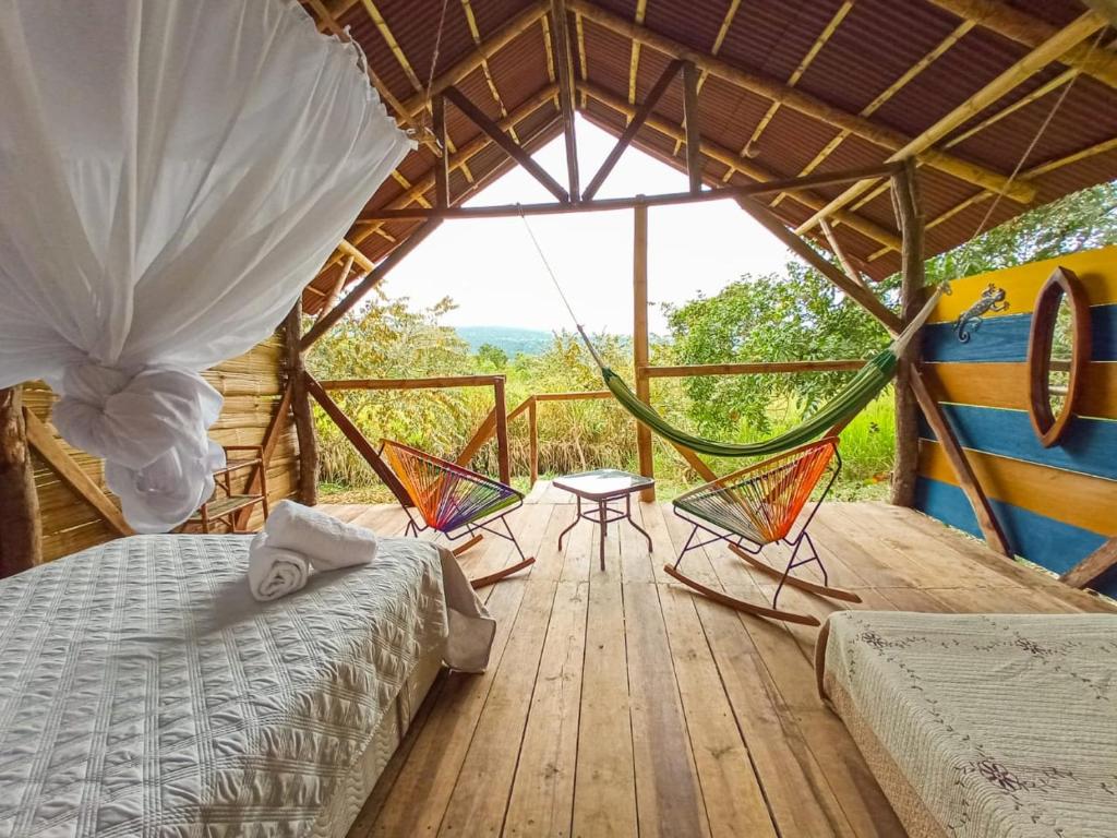 a room with two beds and chairs on a wooden deck at El Cielo Biohospedaje in Tena