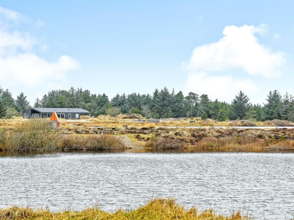 - une vue sur un lac avec une maison en arrière-plan dans l'établissement Holiday home Oksbøl LXXXIV, à Oksbøl