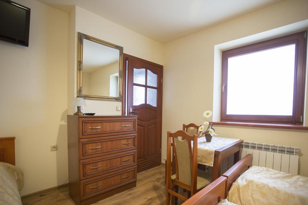een slaapkamer met een dressoir, een tafel en een spiegel bij U Gruloka in Poronin