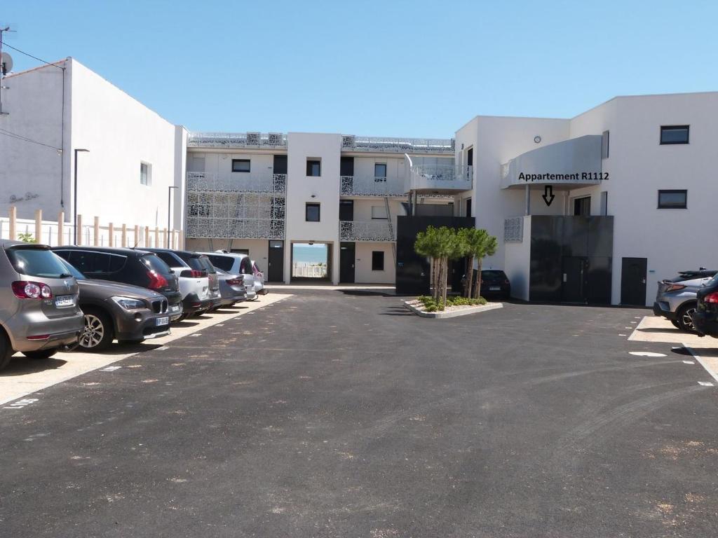 a parking lot with cars parked in front of a building at Appartement PMR avec balcon, 2 chambres, accès direct plage, piscine, parking sécurisé - La Tranche-sur-Mer - FR-1-194-220 in La Tranche-sur-Mer