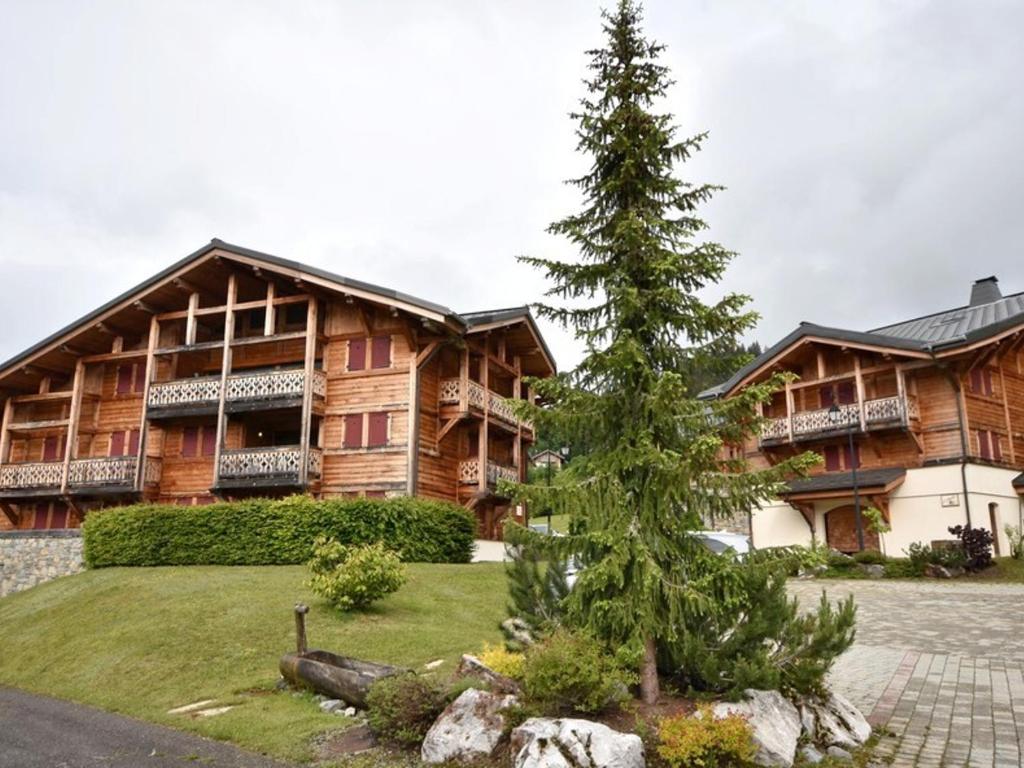 un pin devant un grand bâtiment dans l'établissement Spacieux T4 proche des pistes avec terrasse et parking - 6-8 pers. - FR-1-685-22, aux Gets