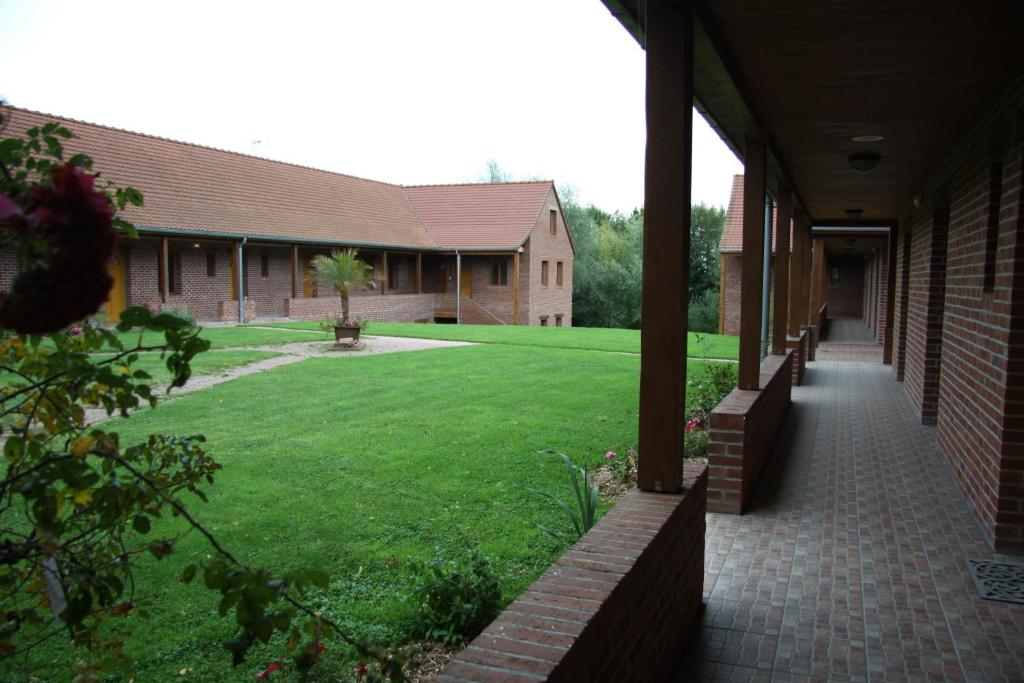 una vista exterior de un edificio con un patio de césped en Hôtel Les Charmilles de Mormal, en Landrecies