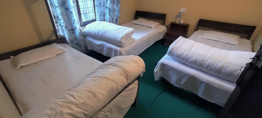 Habitación con 3 camas y sofá. en Diya's Guest House en Bandīpur