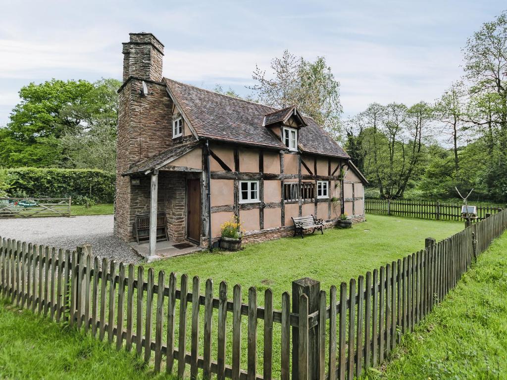 an old house with a fence in front of it at Hollywall Croft in Stoke Prior