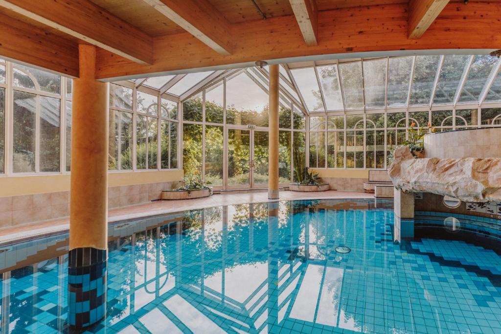 an indoor pool in a conservatory with a glass ceiling at Landhotel Gschirnwirt in Eugendorf