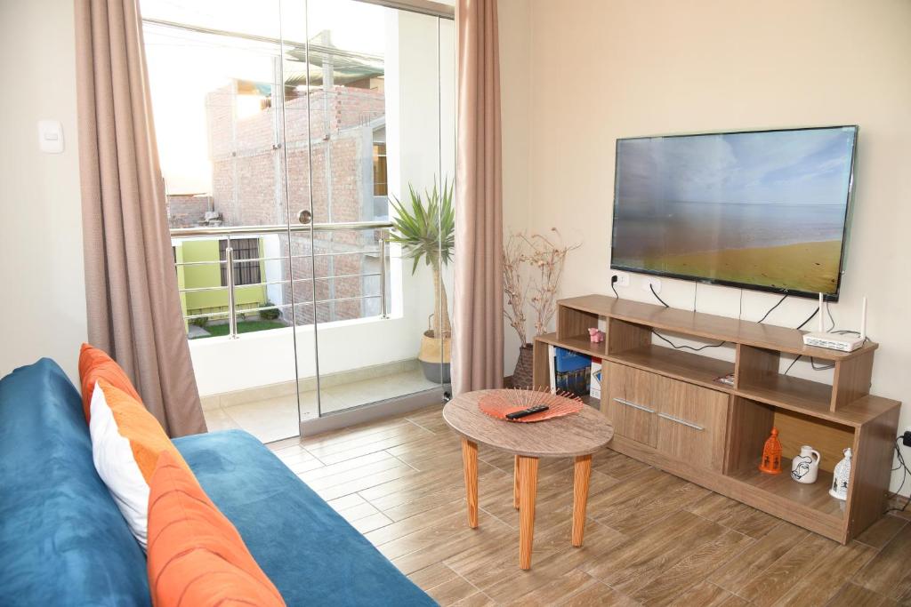 a living room with a blue couch and a flat screen tv at Apartamento Hermoso en Residencial - Huacachina in Ica