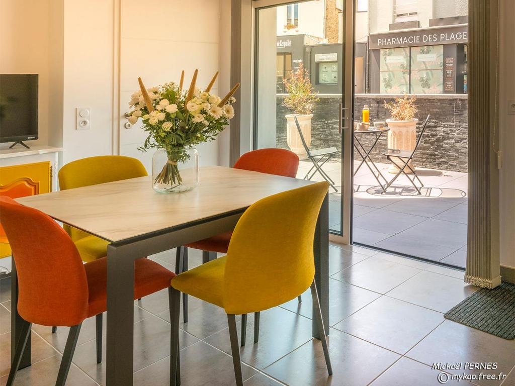 une table à manger avec des chaises et un vase de fleurs dans l'établissement LARMOR-PLAGE : T2 en résidence de standing avec terrasse et parking, à deux pas de la plage et des commerces - FR-1-349-182, à Larmor-Plage