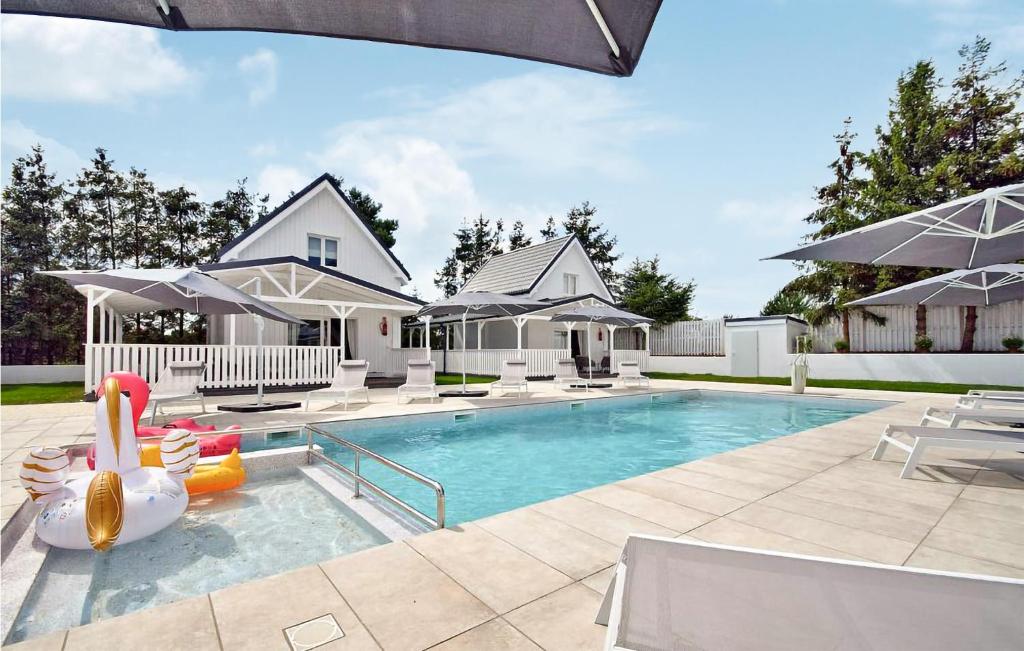 a swimming pool with chairs and umbrellas next to a house at 2 Bedroom Stunning Home In Kolczewo in Kołczewo