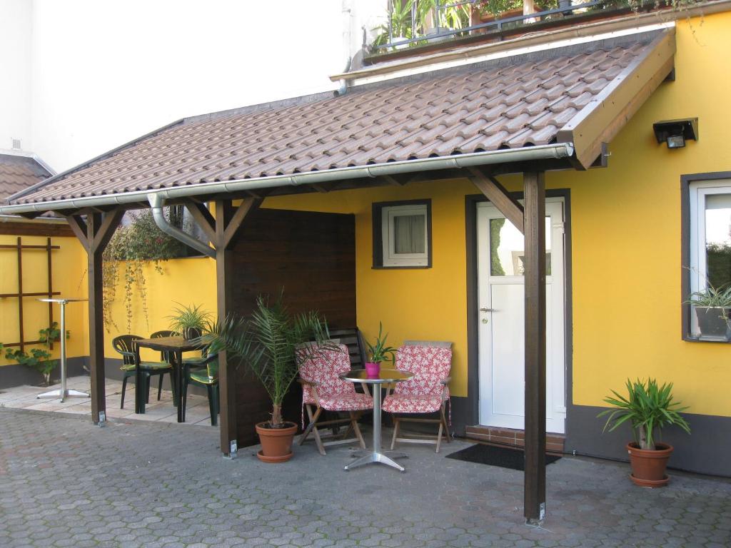 ein gelbes Haus mit einer Terrasse mit Stühlen und einem Tisch in der Unterkunft Apartment Airport in Köln