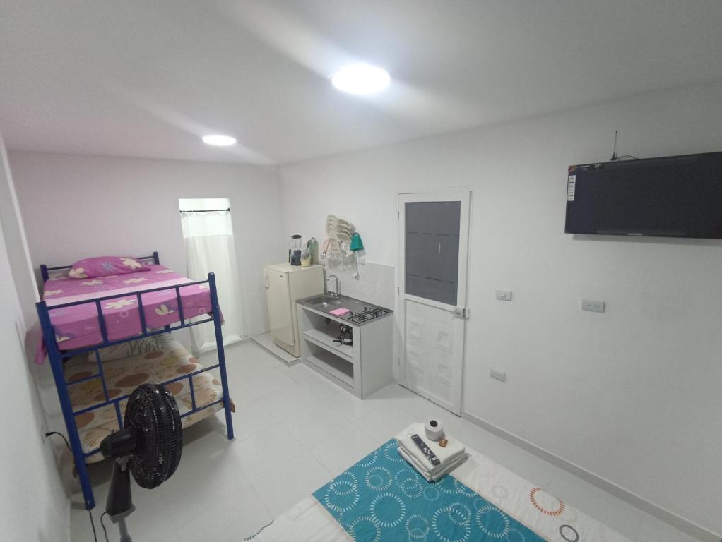 Habitación blanca pequeña con cocina con nevera. en Apartaestudios El Descanso, en Cali
