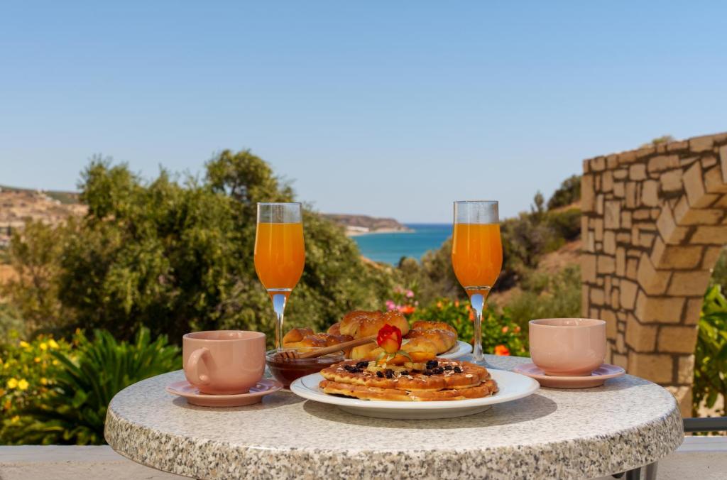 una mesa con un plato de comida y dos vasos de zumo de naranja en Hara's Apartments, en Kastrí